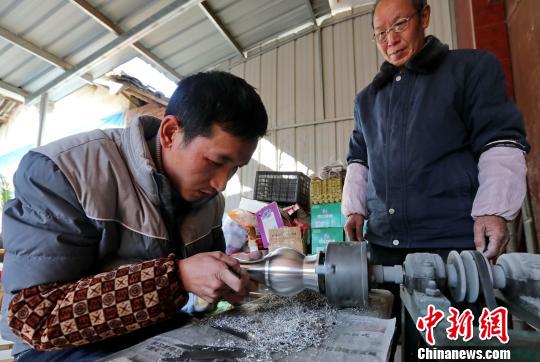 馬華強在父親馬恩明的關(guān)切下，聚精會神對錫壺進(jìn)行反復(fù)拋光�！↑S水林 攝